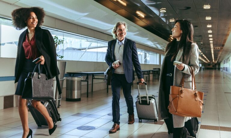 ACI World reveals Airport Service Quality Awards winners Three smiling airport passengers walk together inside a terminal.
