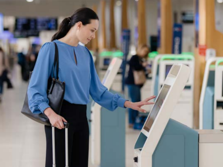 A woman in blue uses a biometric check-in kiosk.