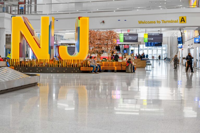 The interior of Newark Liberty International Airport Terminal A with a yellow, reflective statue of the initials NJ.