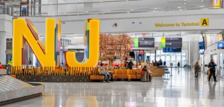 The interior of Newark Liberty International Airport Terminal A with a yellow, reflective statue of the initials NJ.
