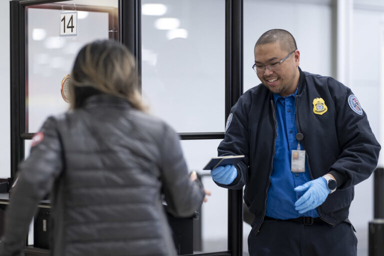 TSA’s passenger experience survey reveals high traveler confidence and satisfaction A smiling TSA officer hands back a passenger’s passport.