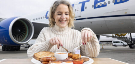 A passenger eats Heathrow’s sustainable ‘Fly Up’ breakfast on the apron, in front of an airplane.