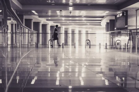 A black and white photo of a woman walking through a terminal.