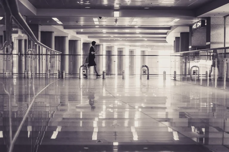 A black and white photo of a woman walking through a terminal.