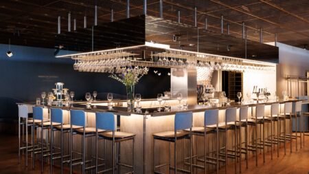 Largest American Express lounge in the Nordic region opens at Stockholm Arlanda Airport The bar in the American Express Lounge by Pontus Frithiof is surrounded by high bar chairs with one wine glass and one water glass each.