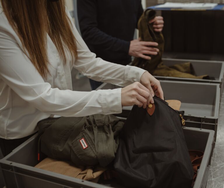 Passengers empty their bags into an airport security tray.