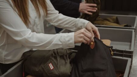 Passengers empty their bags into an airport security tray.