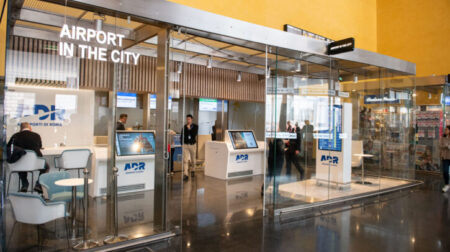 Fiumicino Airport opens check-in and baggage delivery service in center of Rome A glass room with a sign that says, “ Airport in the city”, houses two ADR check-in desks and three staff members.