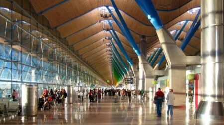 The interior of Adolfo Suárez Madrid-Barjaras Airport with passengers walking through.