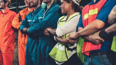 Aberdeen and Glasgow airport workers rejects 4% pay increase A line of workers join hands in high-visibility jackets and hardhat.