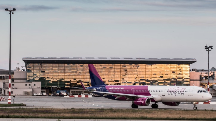 A WizzAir airplane sits parked outside Budapest Airport's terminal.