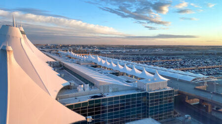 An aerial photo of Denver International Airport with the horizon in the background and a blue sky above