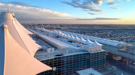 The sun sets over an aerial view of Denver Airport's roofs and car park.