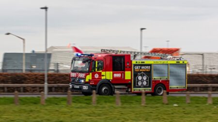 A London fire engine with blue lights races to an emergency.