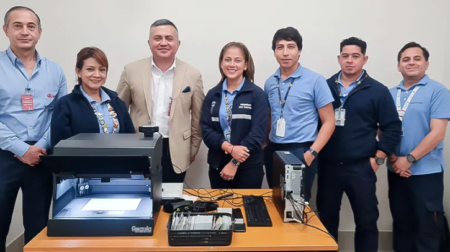 A group of people gather around a desk full of document verification technology.