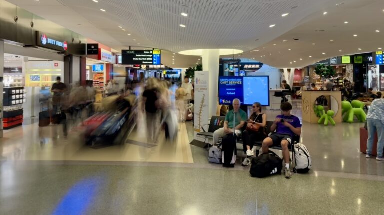 JFKIAT pilots the world’s first mobility cart tracking service A busy airport terminal with people sitting on modular seating and stores and a mobility cart moving through the centre of the image
