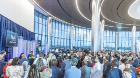 Nashville International unveils Concourse D Extension A large group of people gather by some floor-to-ceiling windows to listen to a man at a podium.