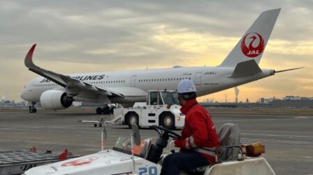 Moonware to test ground traffic control technology with Japan Airlines at Tokyo International A man in high-vis looks at Japan Airlines plane on the runway at Tokyo Airport from his ground operations vehicle.