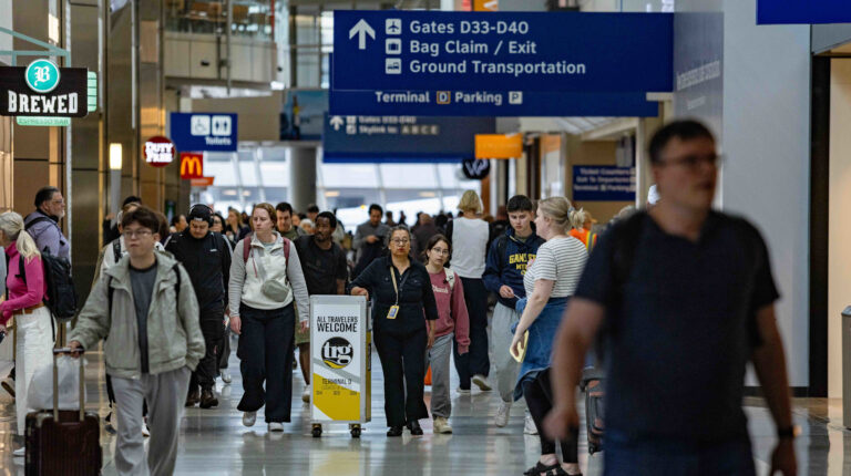 A busy airport concourse with passengers, staff and wayfinding