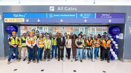 A group of staff stand in front of the new East Security Checkpoint at Denver International Airport to celebrate its opening