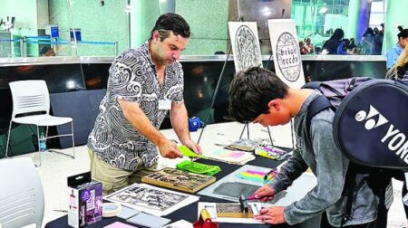 A passenger participates in an art workshop with renowned Miami artist and illustrator Brian Reedy on the airport concourse