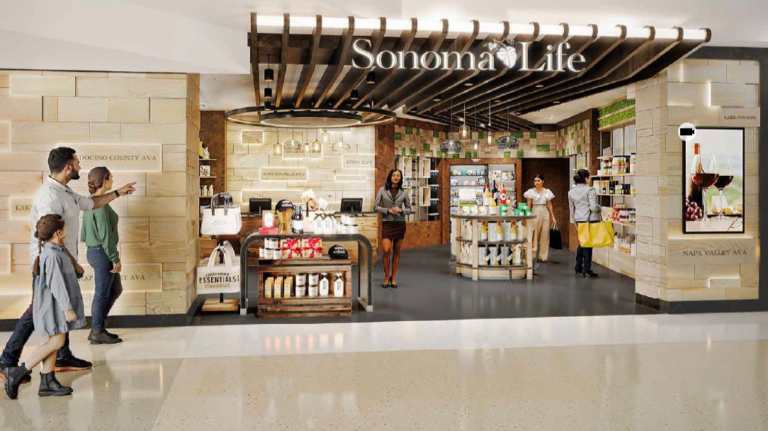 Exterior of Sonoma Life, a California vineyards-themed immersive specialty retail experience opened by Hudson at San José Mineta International Airport, with a member of staff waiting to greet customers