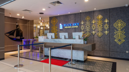 Airport Dimensions opens new lounge at Makassar Sultan Hasanuddin International Airport The entrance to the Blue Sky Lounge at xx, with a desk with three computer screens and the company logo on the wall behind in blue
