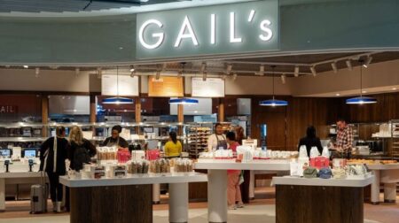 The front of UK baker Gail's' store at London Gatwick Airport, with pastries and sandwiches on display in front of a counter underneath a green nameboard