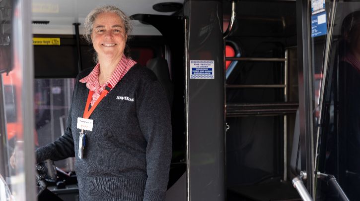 A SyBus member of staff stands on a bus to welcome passengers