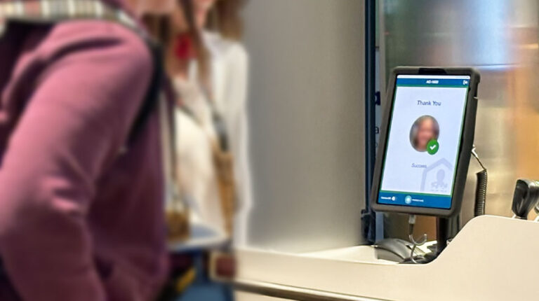 BigBear.ai deploys VeriScan biometric platform at Chicago O’ Hare A passenger wearing a maroon jumper stands in front of screen using BigBear.ai's VeriScan biometric platform