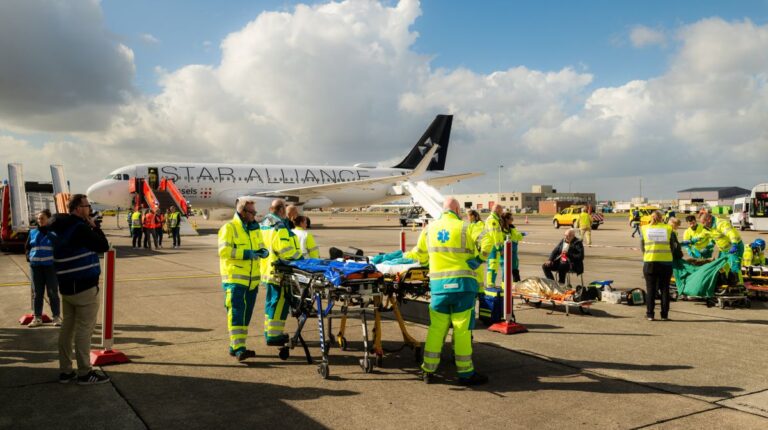 Emergency responders on the airport tarmac at Brussels Airport in hig-vis jackets as part of an emergency exercise with a plane in the background