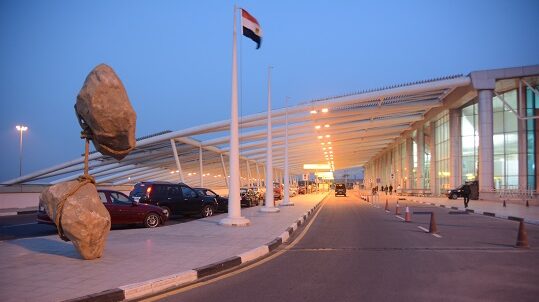 USA invests in Egyptian airport security Exterior of Cairo International Airport at dusk, with cars parked in drop-off bays