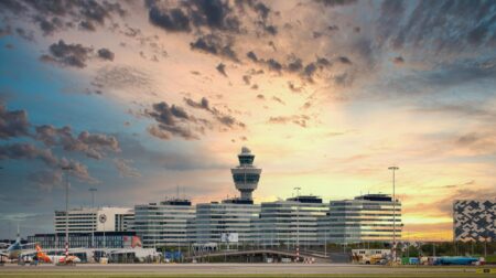 External shot of Amsterdam Airport Schiphol with the sun low in the sky and scattered clouds