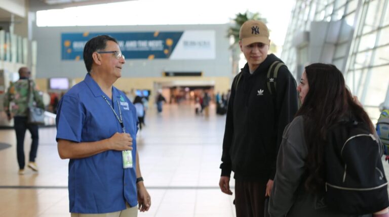 Passengers with nonvisible disabilities talk with airport staff on the concourse at San Diego International Airport.