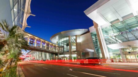 The entrance to San Diego airport (SAN) at night-time, with blurred red lights from automobiles passing in front.