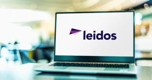 A laptop with the Leidos brand logo displayed on the screen, in an airport terminal.