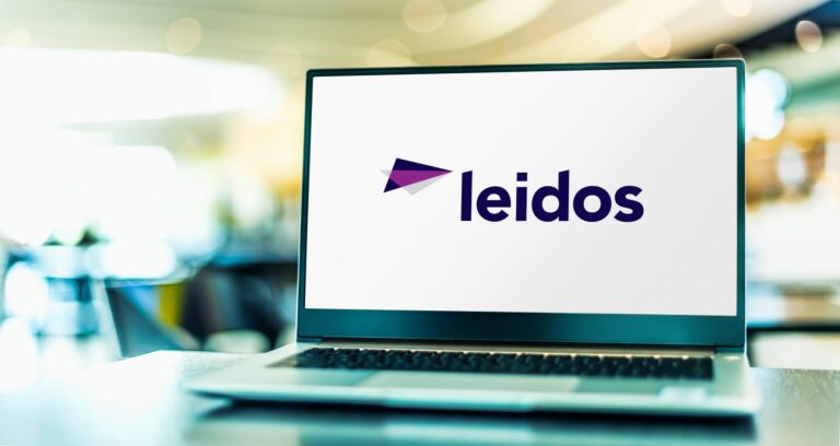 A laptop with the Leidos brand logo displayed on the screen, in an airport terminal.
