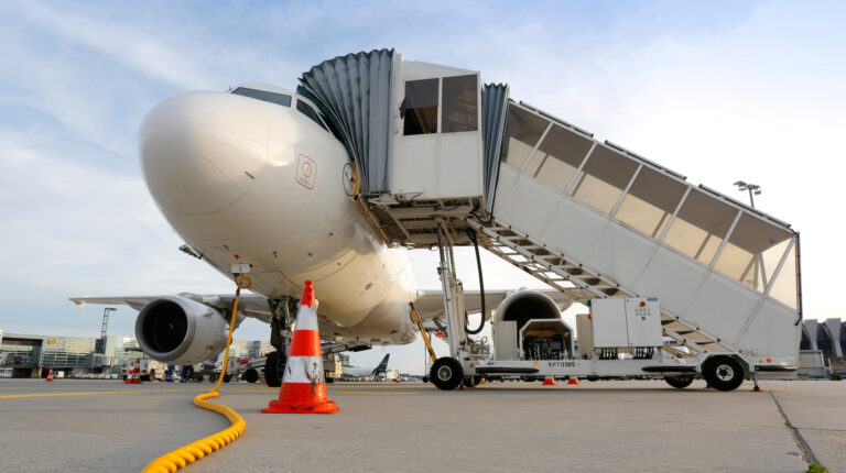 A plane parked at a gate at an airport with stairs leading up to the open door.