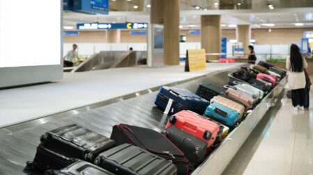 Baggage of different colours on a carousel at an airport.