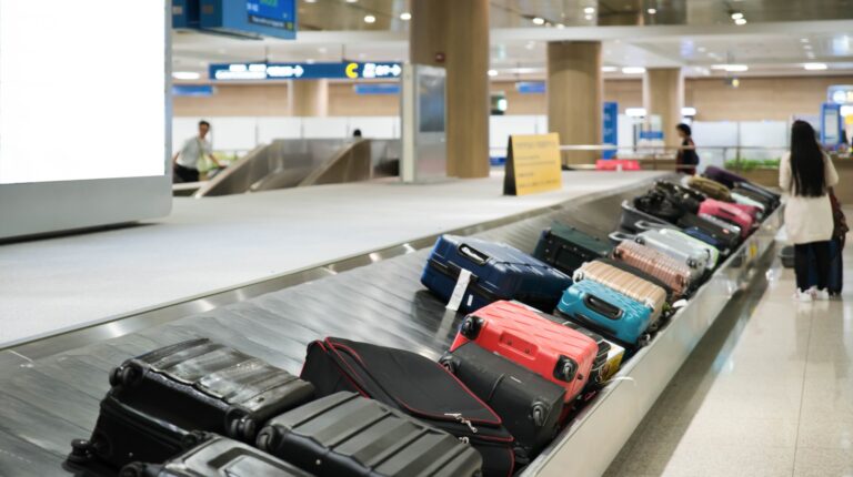 Baggage of different colours on a carousel at an airport.