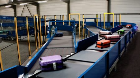 An Alstef Group baggage handling system, with various pieces of luggage on an array of conveyor belts.