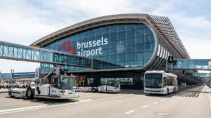 Exterior front of Brussels Airport, with the airport name written in large white lettering and the logo in red on large glass windows.