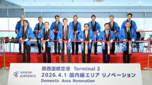 Kansai Airports representatives in dark suits and wearing blue gowns cut the ribbon to marek the oening of the new domestic area in Kansai International Airport's Terminal 2.