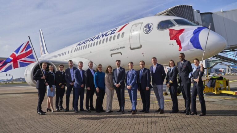 Representatives of Air France and DHL Supply Chain stand in front of an Air France branded jet on the airport tarmac holding UK and France flags.