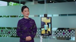 An airline and airport represetative stands in front of a digital ID check-in touchscreen system on the airport concourse.