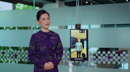 An airline and airport represetative stands in front of a digital ID check-in touchscreen system on the airport concourse.