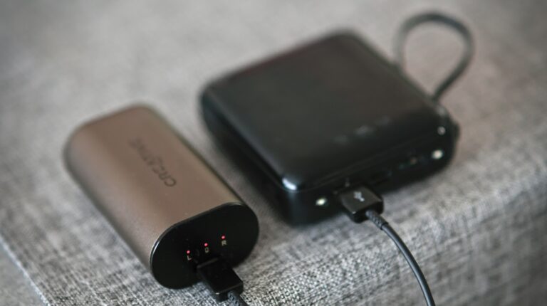 A small grey power bank and a large black power bank on a table.