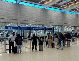 The security lanes at Kansas City International Airport, wiht passengers waiting in lines and security personnel standing at the sides.