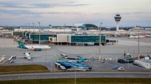 External aerial photograph of Munich Airport with the terminal in the centre and plans parked in the foreground.