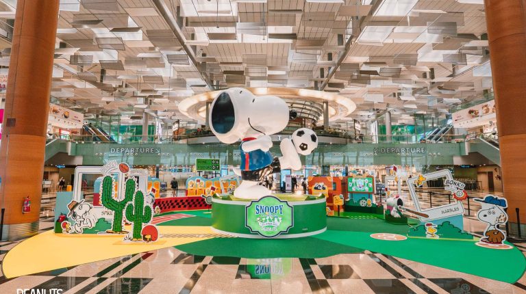 Wide-view photo of the Peanuts sports-themed installation at Changi Airport, with a large Snoopy in the center of the terminal.